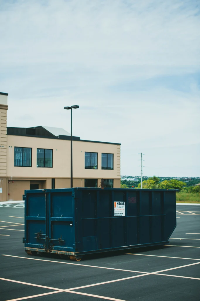 Dark blue roll-off dumpster sitting in a parking lot