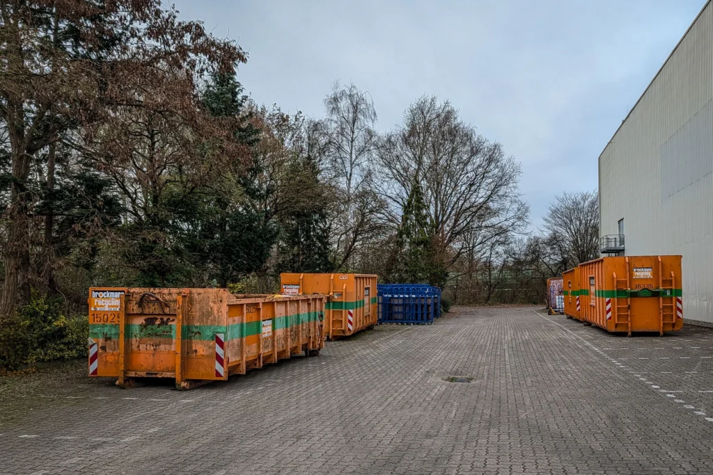 Several orange roll-off containers staged in a paved yard